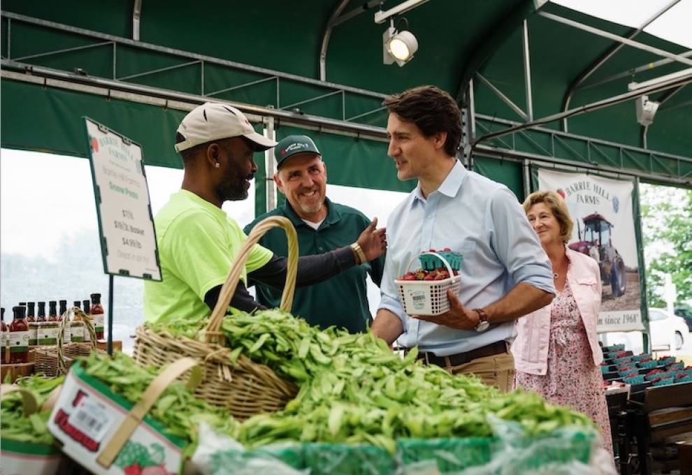 Temporary foreign worker Shawn Agard (L) greets Prime Minister Justin Trudeau with Morris Gervais, owner, Barrie Hill Farms looking on. Hon. Helena Jaczek listens to the exchange. 