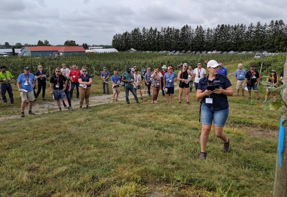 The capacity crowd was split into three groups for in-orchard tours at Archibald’s Orchards and Winery, Clarington, Ontario. In this photo, Ontario tree fruit specialist Erika DeBrouwer talks about trials with the pollen tube growth model. 